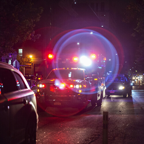Ambulance with lights flashing on city street at night.