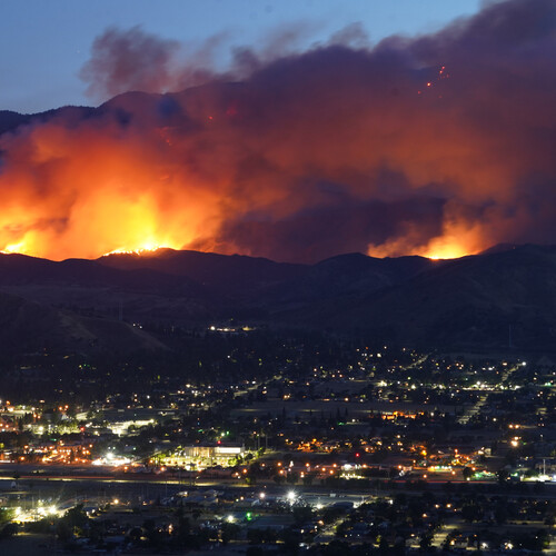 A large wildfire burns in the mountains above a California city.