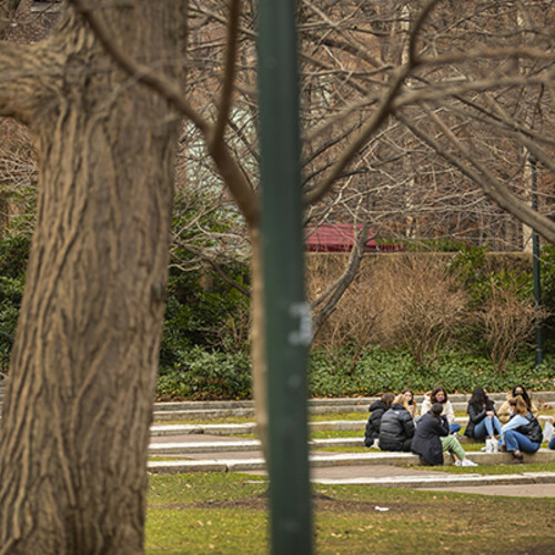 Masked students sit outside on Penn's campus