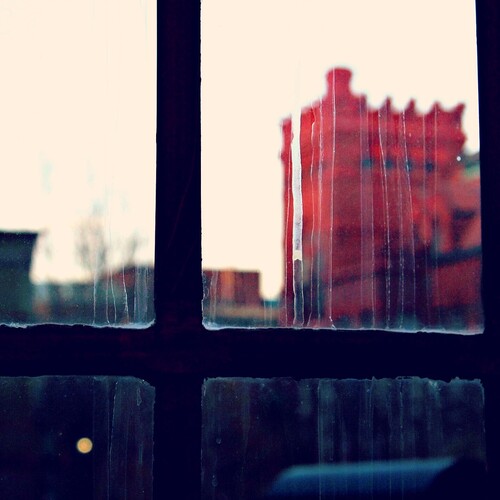 Rain streaks on a gridded window with an image of a red building behind