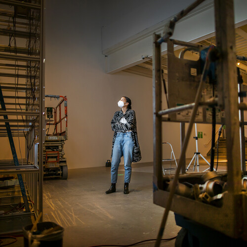 artist looking up at light installation surrounded by construction equipment 