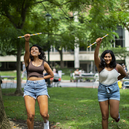 two students dancing with sticks