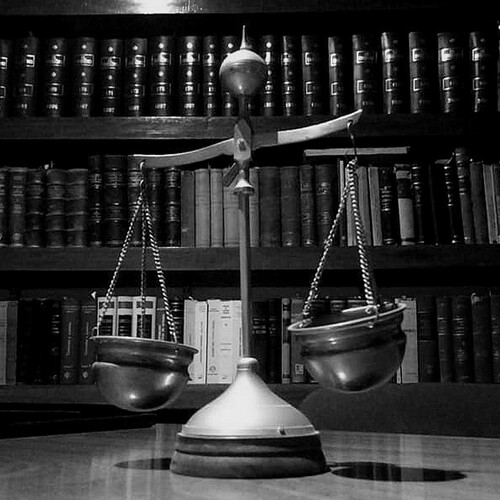 A close up to the an ornamental scale in an office with law books on shelves behind it.