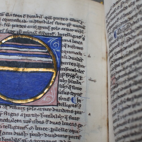 Open pages of John Trevisa book with ancient language and a round blue symbol among the text.
