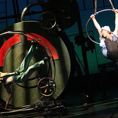 Cirque Mechanics performing on stage with wheels and hanging loops. 