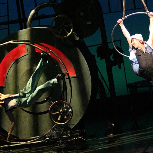Cirque Mechanics performing on stage with wheels and hanging loops.
