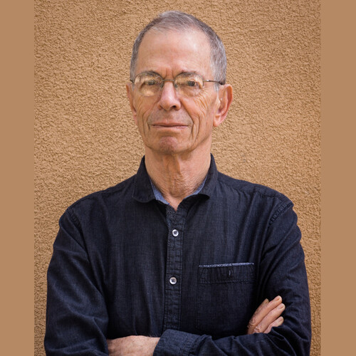 Peter Sterling standing arms crossed in front of a tan textured wall. 