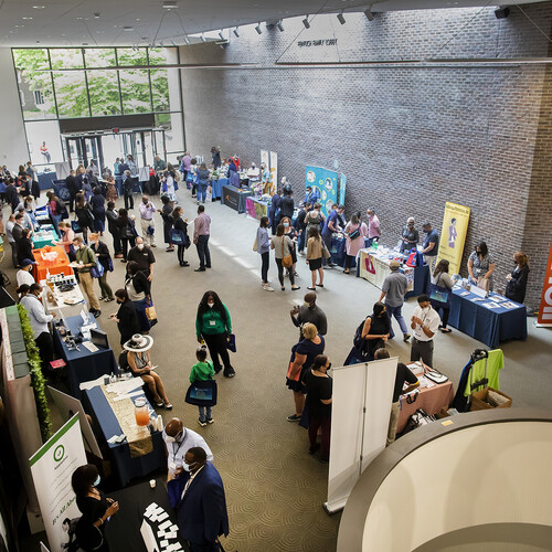 People walking around a lobby where various tables are set up.