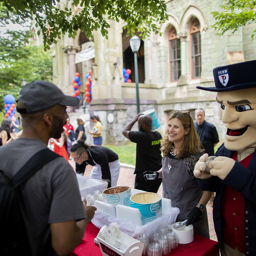 Liz Magill scoops ice cream and smiles with the Quaker mascot