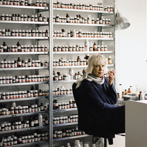 Sissel Tolaas in front of many bottles of scents.