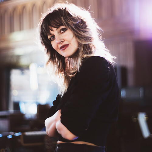 Anais Mitchell crossing her arms and backlit by street lights