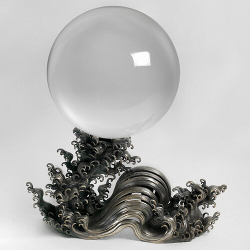 Picture of a crystal ball laying on metal in the shape of waves.