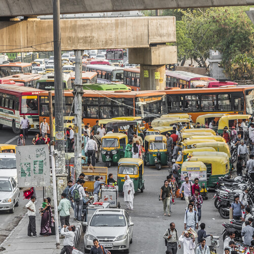 Traffic in New Delhi with pedestrians, buses, and tuktuks.