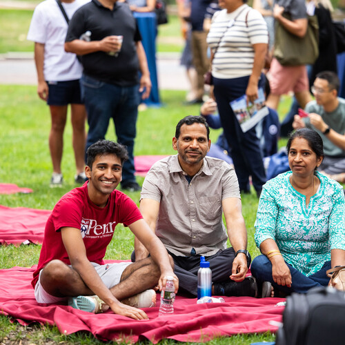 Students and families sitting on tablecloths on College Green.