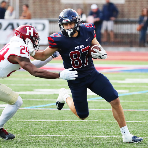 Joshua Casilli stiff arms a Harvard defender while running with the ball during a game at Franklin Field.