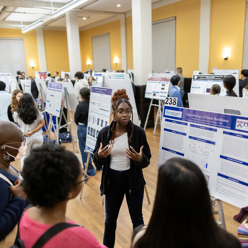 A student discusses their poster with others at the CURF poster expo.