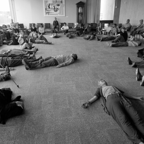 Individuals, either laying on the ground or crossing their legs, close their eyes to listen and feel the surroundings.