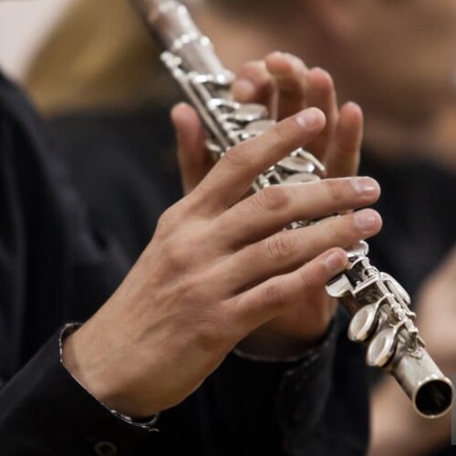 A flute musician playing the flute in an orchestra.