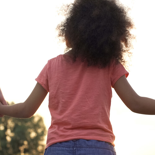 A child holding the hands of two adults.