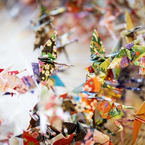 Numerous tiny folded origami cranes in a basket.