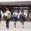 six kids in private school uniforms and backpacks running into school