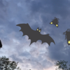 Bats and moths fly over statue with dark sky in background