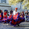 Street dancers in colorful costumes being cheered on by bystanders 