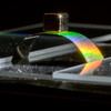 A metallic arch on a surface reflecting a rainbow prism.
