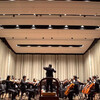 Symphony orchestra mid-performance with sprawling stage behind them