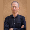 Peter Sterling standing arms crossed in front of a tan textured wall. 