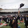 Graduates on Franklin Field throw graduation caps in the air.