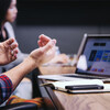 Two people work on laptops at a conference table. 