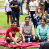 Students and families sitting on tablecloths on College Green.