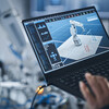 A person programming a robotic arm with a laptop.
