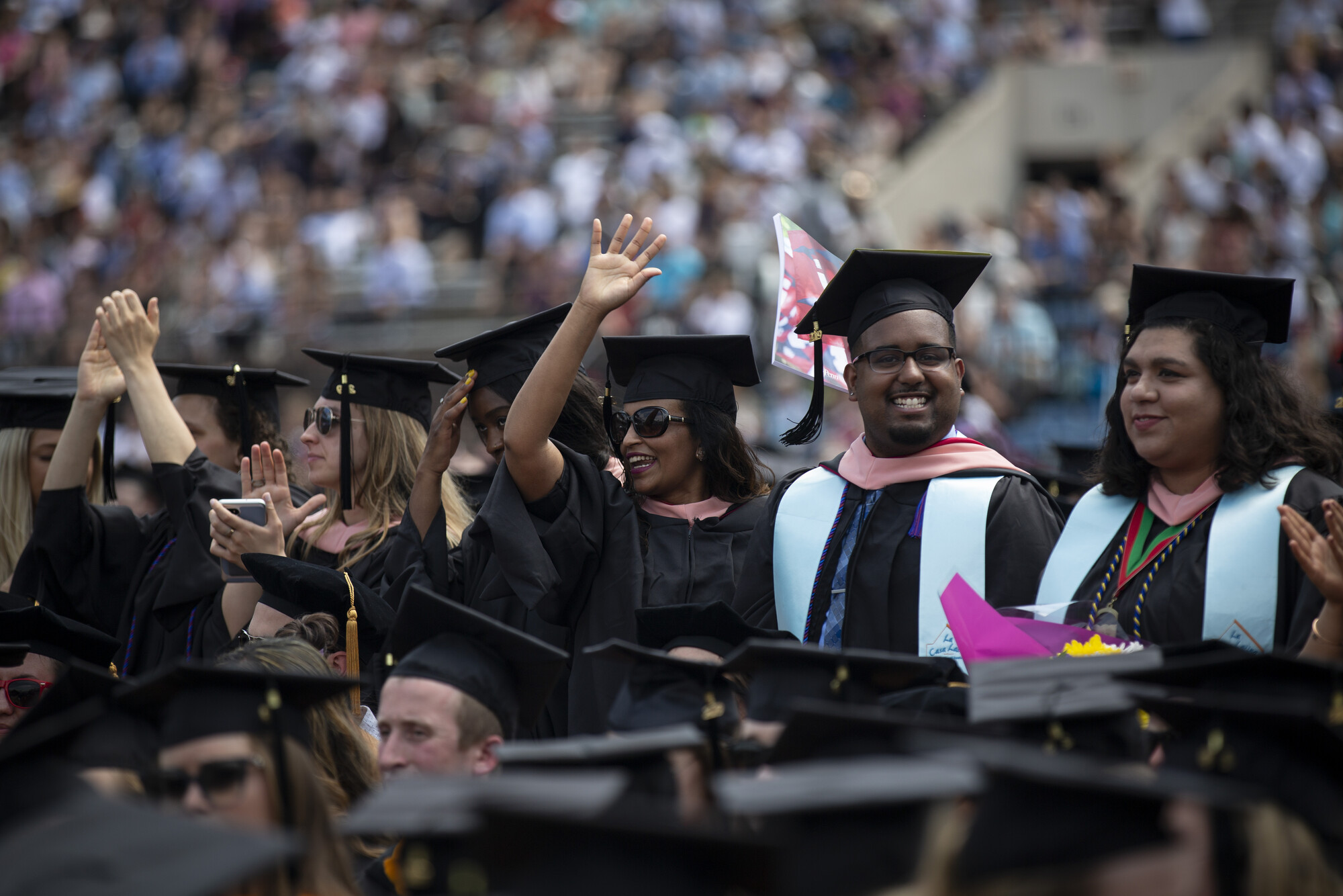 Graduating students stand and wave during commencement.