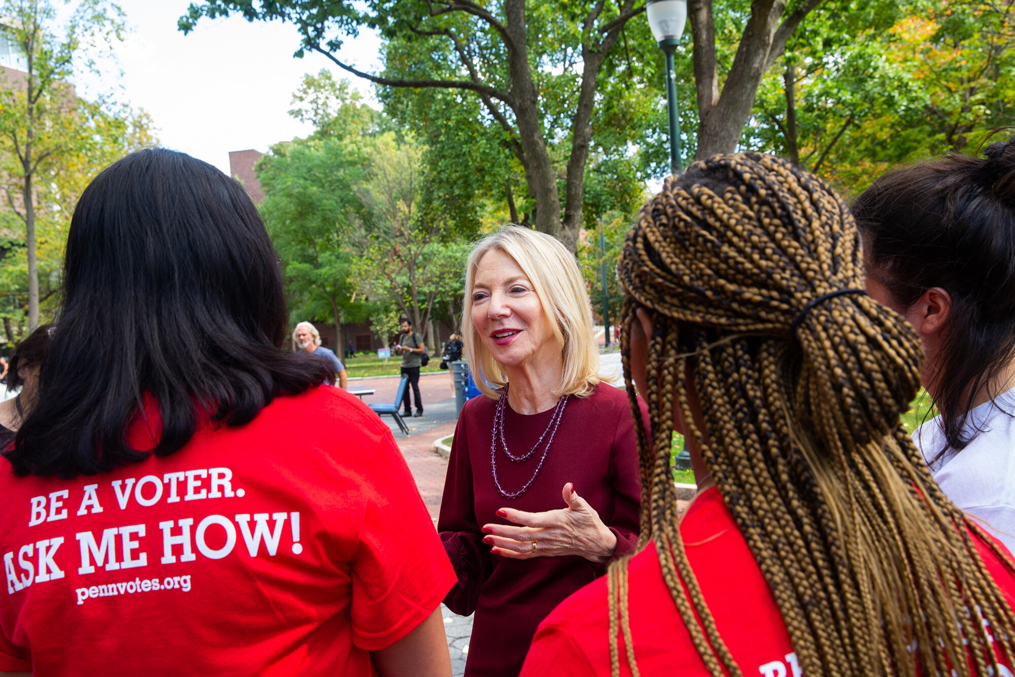 Amy Gutmann talks with two members of Penn Leads the Vote on College Green.