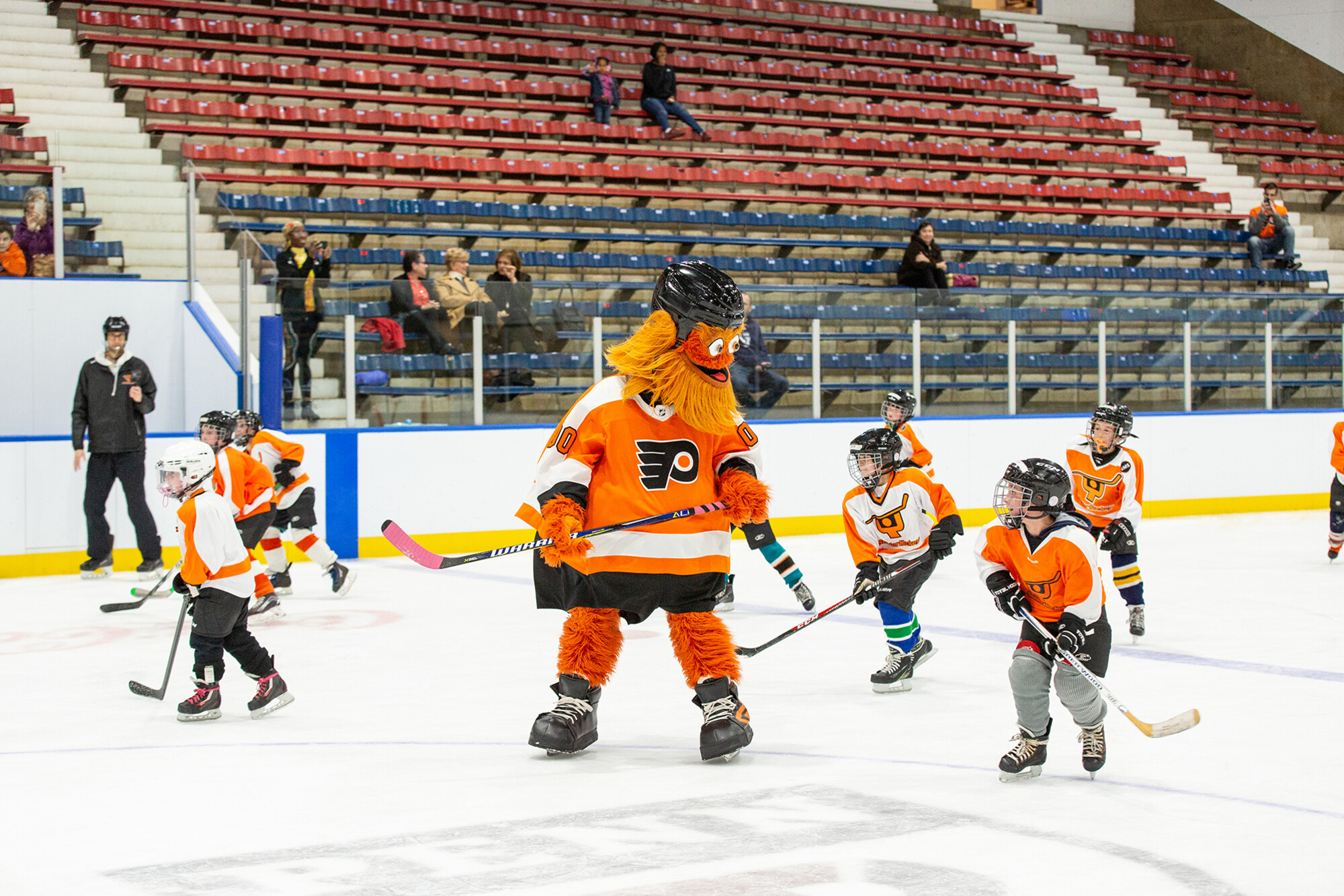 Gritty skating on the ice with members of a youth hockey league