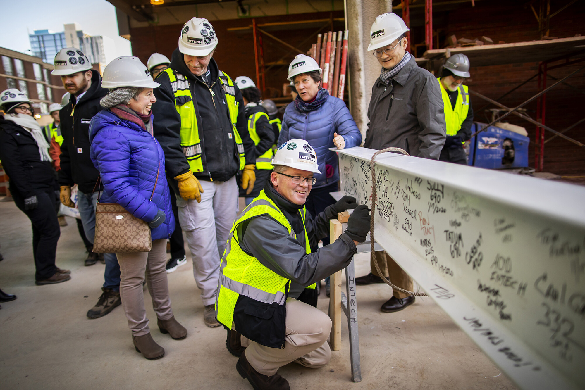 Members of the New College House West project gather around the final beam for signing