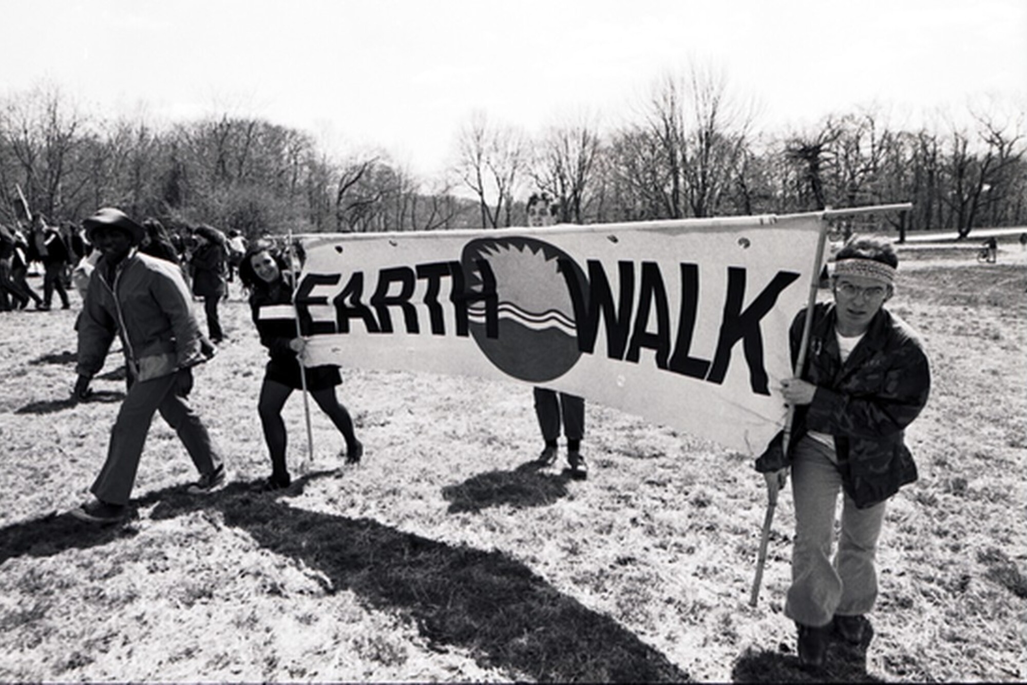 People walking in a park hold a banner reading "Earth Walk"
