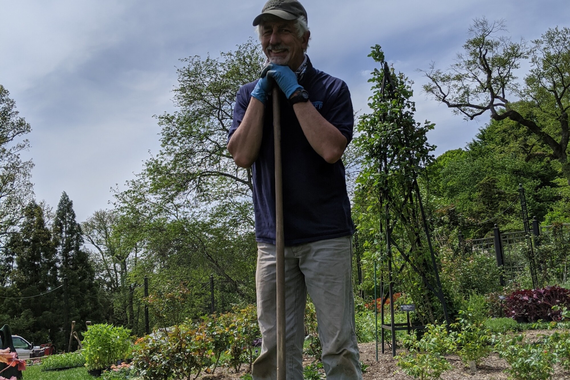 Gardener leans against shovel and smiles
