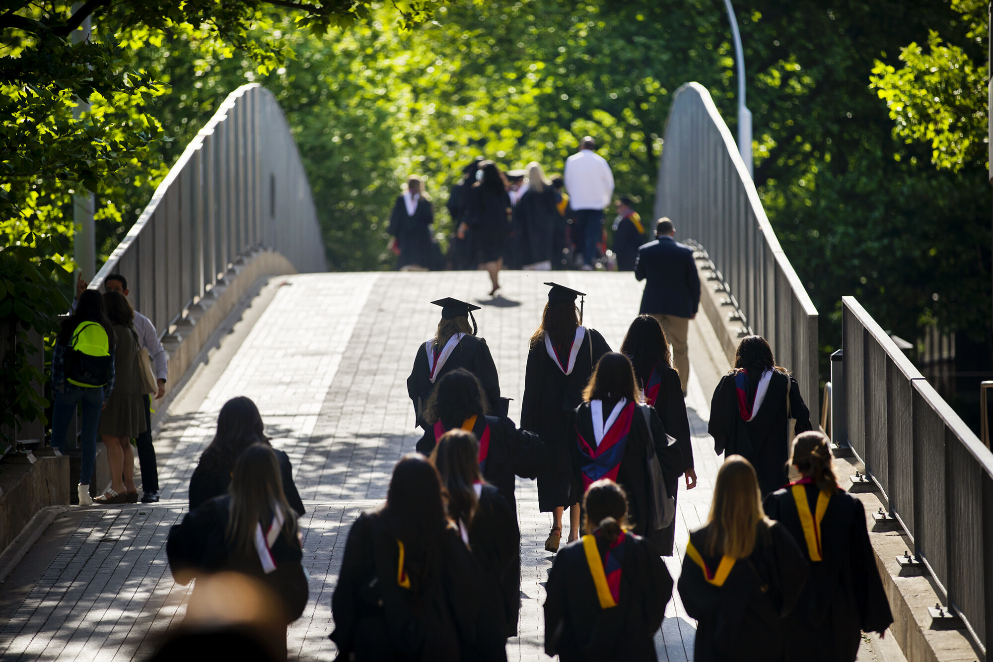 graduates walking over 38th street bridge