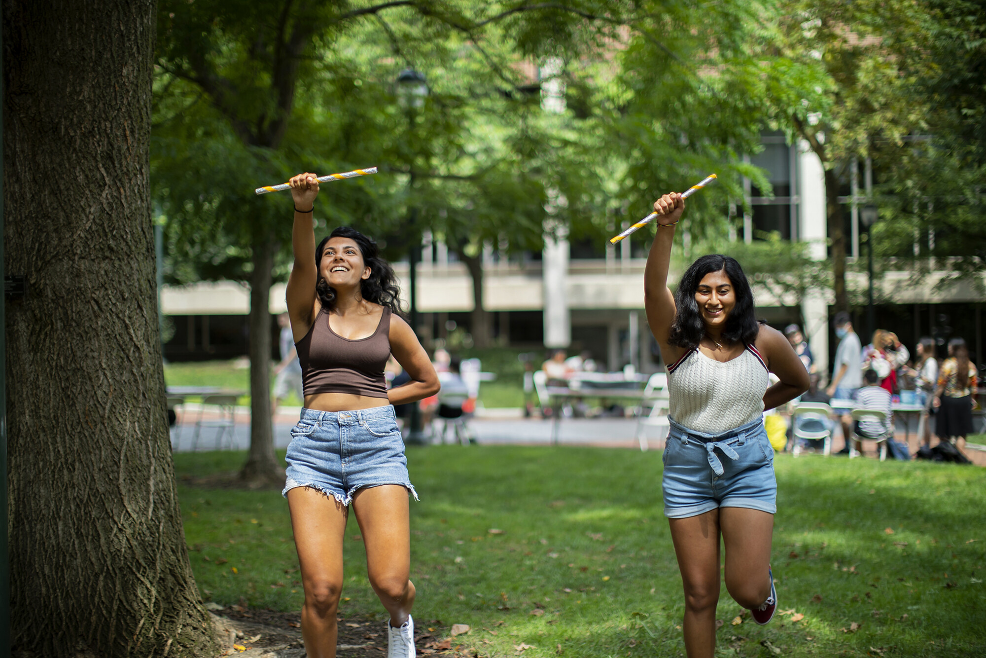 two students dancing with sticks