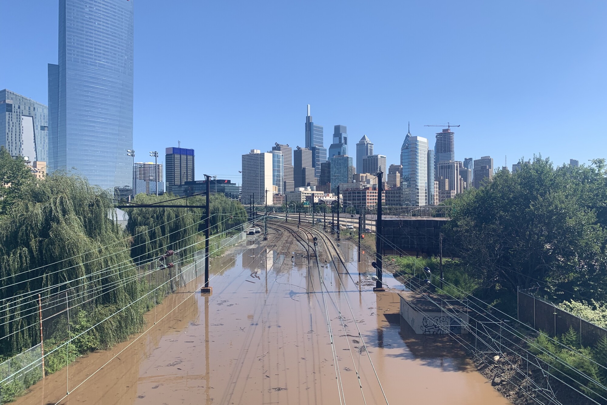 Schuykill River flooded along train tracks with cityscape of Philadelphia in distance.