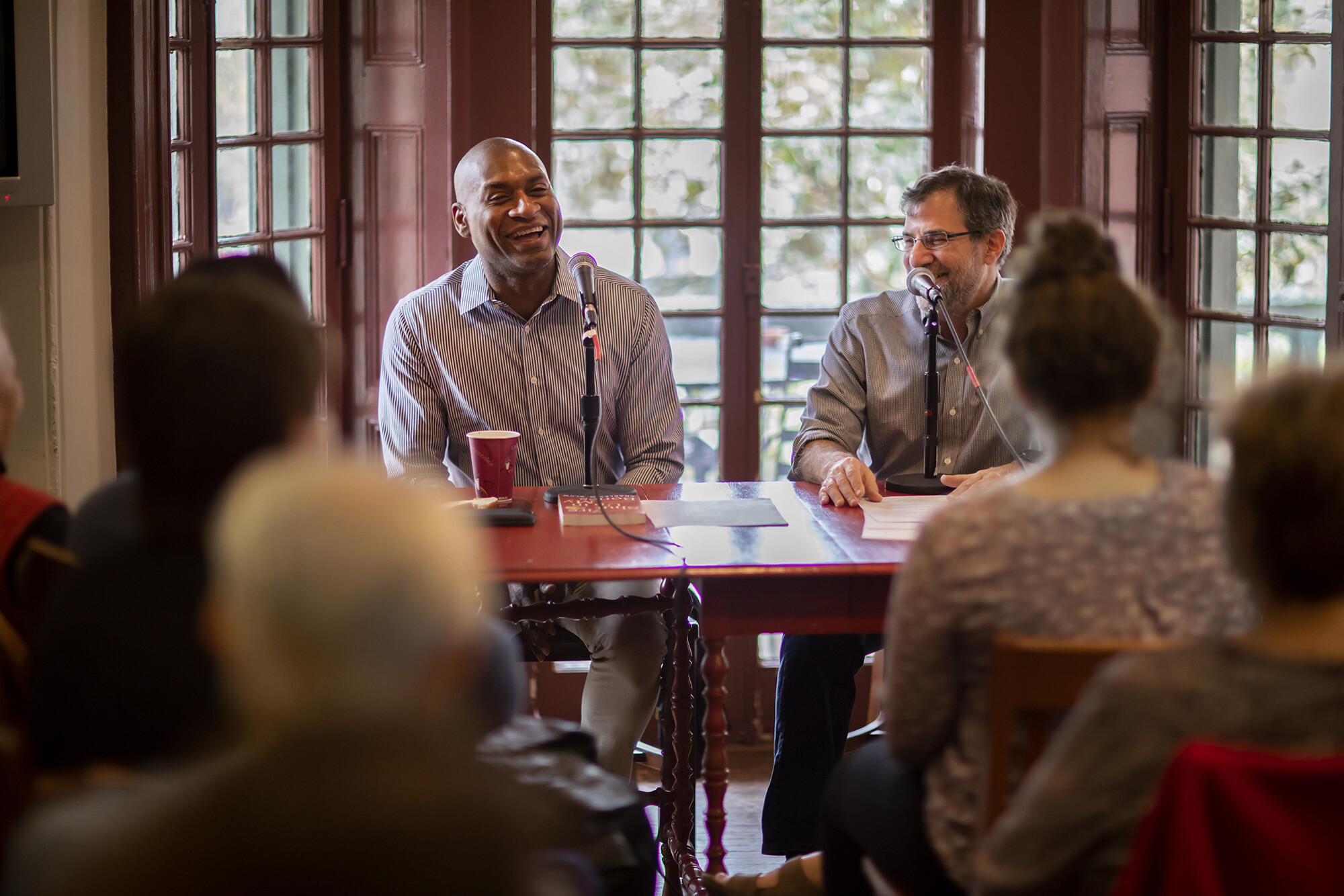 Charles Blow and Al Filreis seated at a table in front of a crowd at the Kelly Writers House.