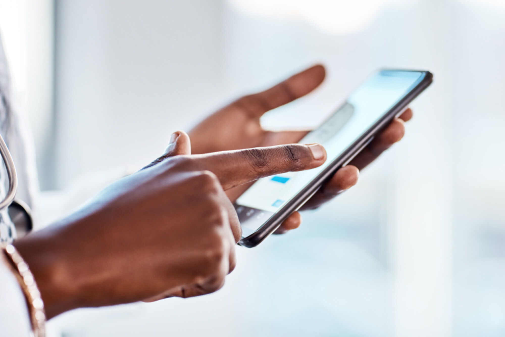 Person with stethoscope using a smartphone.