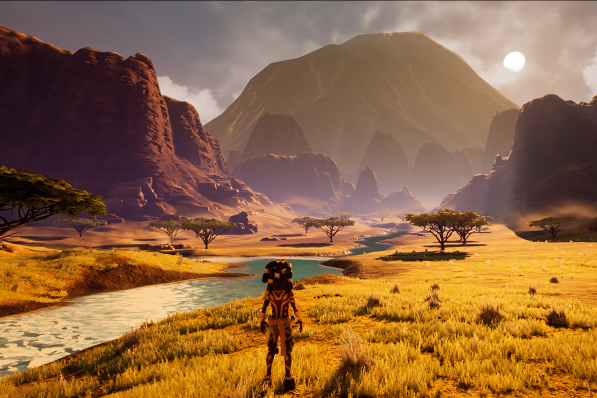 Video game rendering of a character standing by a river in a large valley surrounded by mountains.