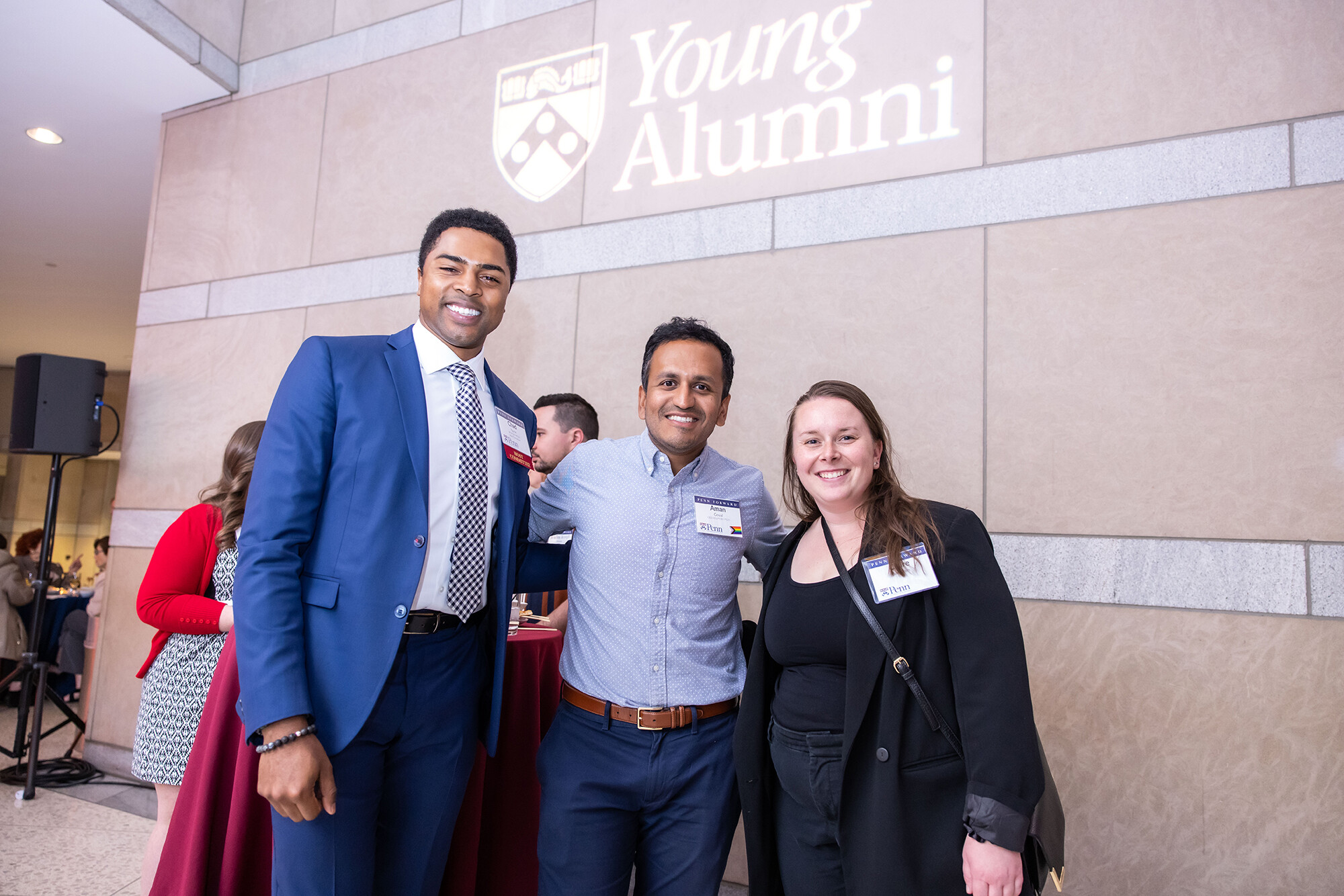 three alumni stand under light that reads "young alumni"