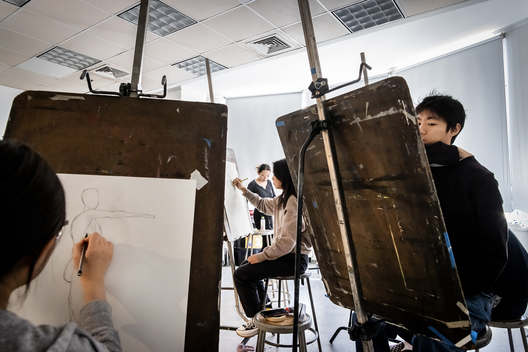students work on easels in a drawing class