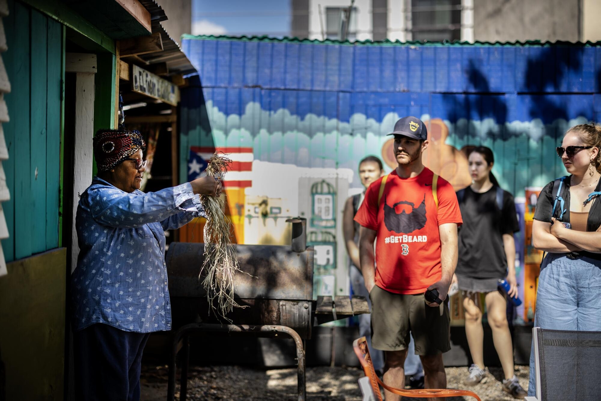 A volunteer with an urban farm holds up roots to Penn students.