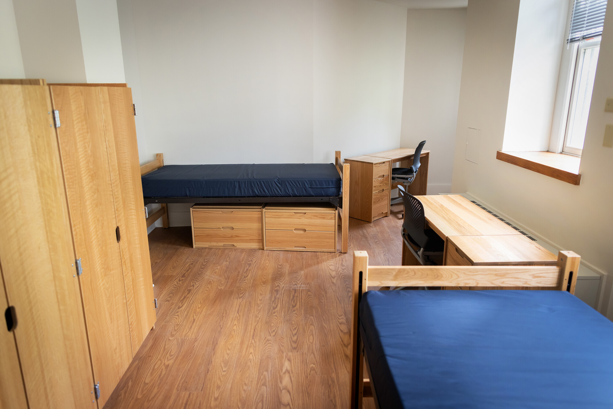 A bed, closet, and series of desks. 